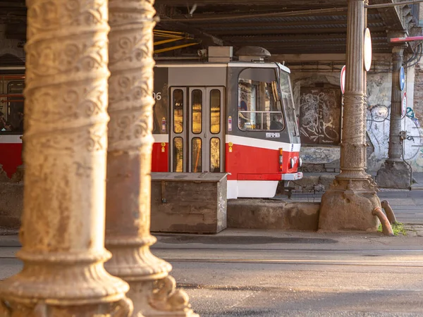 Brno şehrinde bir caddede oyulmuş sütunların arkasındaki tramvayın görüntüsü.