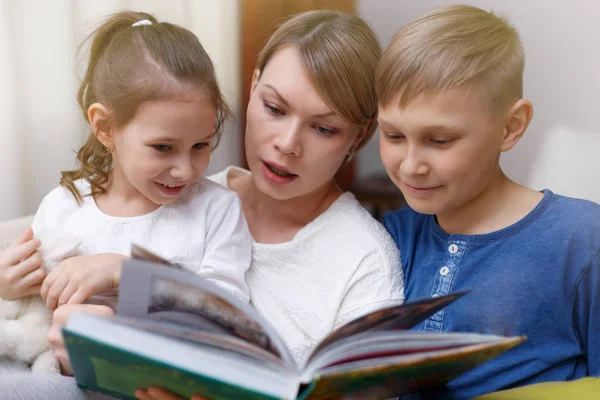 Piękne matki to czytając książkę, aby jej dzieci. Siostra — Zdjęcie stockowe