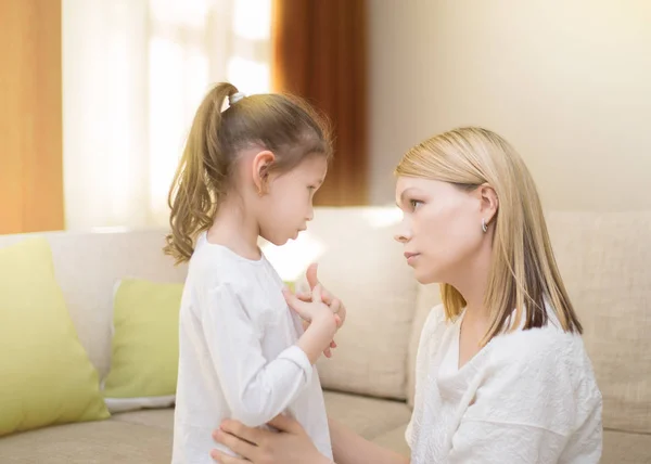 Beautiful mother is comforting her sad little daughter at home. — Stock Photo, Image