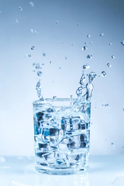 Ice cube into a glass of water — Stock Photo, Image