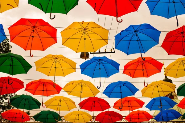 Coloridas centenas de guarda-chuvas flutuando acima da rua — Fotografia de Stock