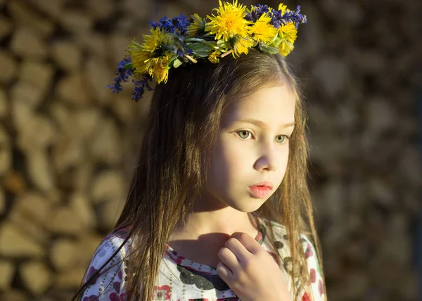 Joven chica bonita en flores corona se queda cerca de la pila de madera en el pueblo . — Foto de Stock