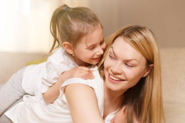 Annem ve onun sevimli kız çocuk, gülümseyerek ve sarılma oynuyorlar. Mutlu anneler günü.