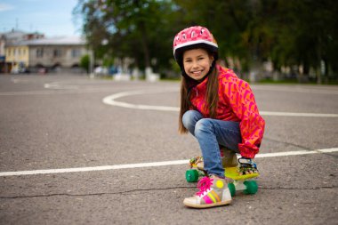 Güzel bir yaz parkında kaykay süren küçük tatlı bir kız.