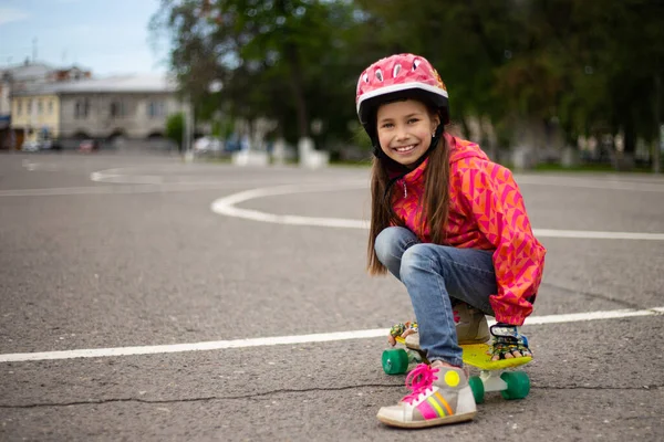 Roztomilý malý preteen dívka na koni na skateboardu v krásné letní park — Stock fotografie