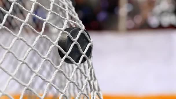 Хоккейная шайба летает в сеть на хоккейных досках с желтой полосой. В замедленной съемке — стоковое видео
