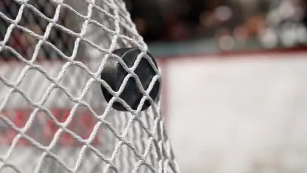 Hokejový puk letí do sítě na hokej desek s červeným pruhem. V pomalém pohybu