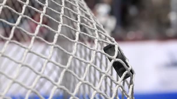 La rondelle de hockey vole dans le filet sur des planches de hockey avec une bande bleue. Le mouvement au début est accéléré puis lentement — Video