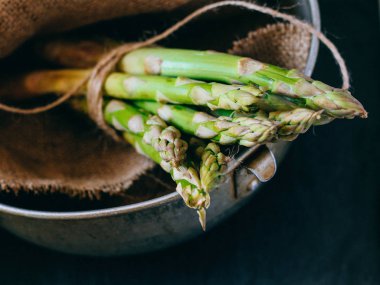 Bir avuç siyah mazisi üzerinde taze yeşil kuşkonmaz
