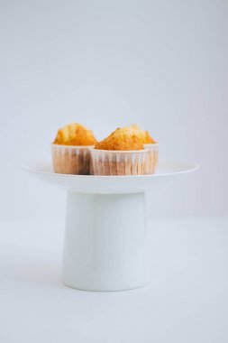 Turuncu muffins beyaz zemin üzerinde bir kek standı. Minimalis