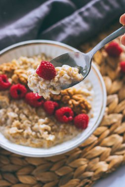 Sabah kahvaltı, ahududu ve üzerinde metal bir kaşık ceviz ile süt yulaf ezmesi