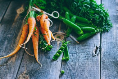 Taze havuç ile yeşil üstleri ve pods bezelye bir ahşap arka plan, hasat, sonbahar