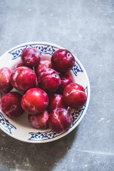 Erik bir desen ile beyaz bir seramik tabak içinde farklı çeşitleri. Gri beton zemin. Üstten görünüm. Bahçe, tarım, hasat kavramı.