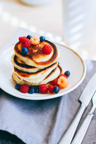 Breakfast, lush pancakes with fresh berries, raspberries and blueberries and a cup of tea