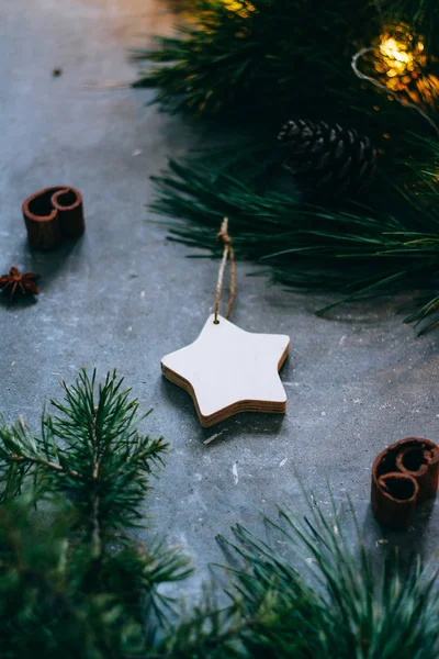 Χριστούγεννα ή Πρωτοχρονιά φόντο, κλαδιά ενός χριστουγεννιάτικου δέντρου και vintage παιχνίδια, ξύλινο αστέρι σε γκρι φόντο. Χριστουγεννιάτικη διακόσμηση. Μια λαμπερή γιρλάντα. — Φωτογραφία Αρχείου