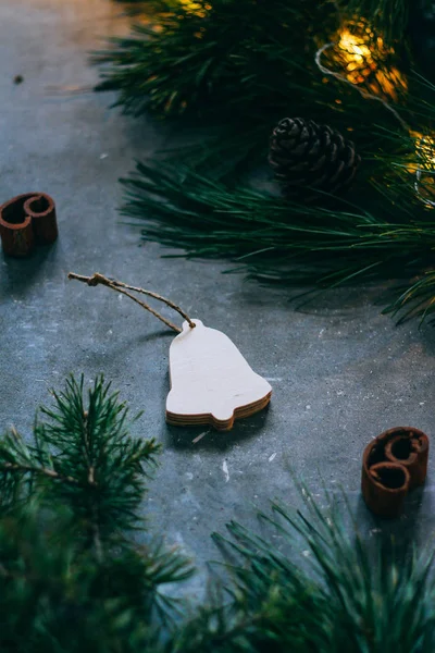 Χριστούγεννα ή Πρωτοχρονιά φόντο, κλαδιά ενός χριστουγεννιάτικου δέντρου και vintage παιχνίδια, ξύλινη καμπάνα σε γκρι φόντο. Χριστουγεννιάτικη διακόσμηση. Μια λαμπερή γιρλάντα. — Φωτογραφία Αρχείου