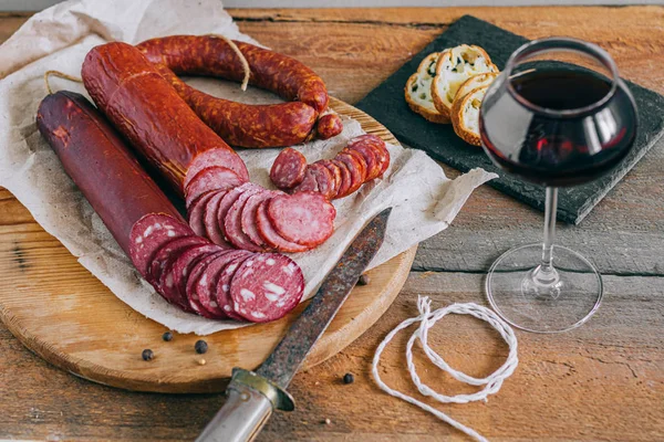 Surtido de embutidos ahumados, aperitivo al vino tinto sobre un fondo de madera —  Fotos de Stock