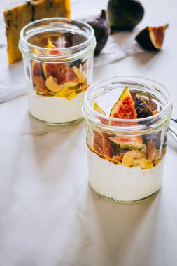 Ekşi krema, vanilya, incir, fındık, bal ve mavi peynir bir bardak mermer arka planda