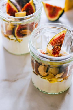 Ekşi krema, vanilya, incir, fındık, bal ve mavi peynir bir bardak mermer arka planda