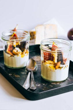 Ekşi krema, vanilya, incir, fındık, bal ve mavi peynir siyah bir tepside, mermer arka planda