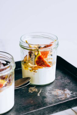 Ekşi krema, vanilya, incir, fındık, bal ve mavi peynir siyah bir tepside, mermer arka planda