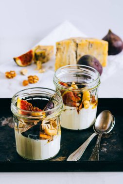 Ekşi krema, vanilya, incir, fındık, bal ve mavi peynir siyah bir tepside, mermer arka planda