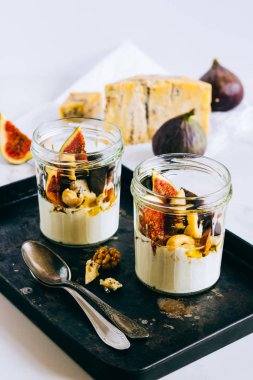 Ekşi krema, vanilya, incir, fındık, bal ve mavi peynir siyah bir tepside, mermer arka planda