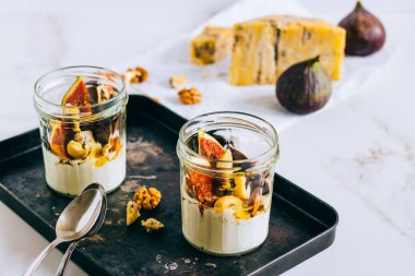 Ekşi krema, vanilya, incir, fındık, bal ve mavi peynir siyah bir tepside, mermer arka planda