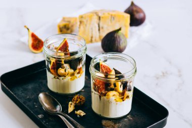 Ekşi krema, vanilya, incir, fındık, bal ve mavi peynir siyah bir tepside, mermer arka planda