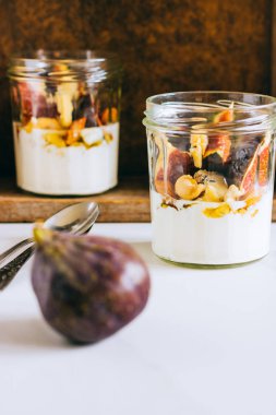 Ekşi krema, vanilya, incir, fındık, bal ve mavi peynir, ahşap bir kutuda, mermer arka planda.