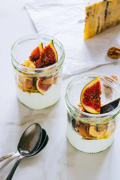 Ekşi krema, vanilya, incir, fındık, bal ve mavi peynir bir bardak mermer arka planda