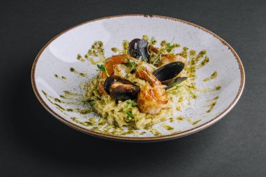 Karidesli orzotto ve siyah arka planda pesto.