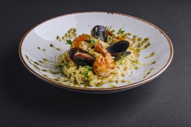 Karidesli orzotto ve siyah arka planda pesto.