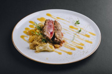 Siyah arka planda taze bezelye filizi ve kinoalı ördek göğsü filetosu.