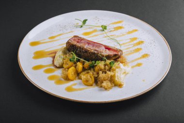 Siyah arka planda taze bezelye filizi ve kinoalı ördek göğsü filetosu.