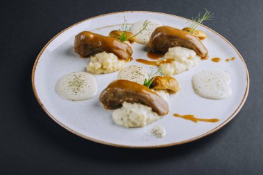 Domuz mantarlı kuskus garnitürlü kuzu dilleri ve siyah arka planda taze bezelye filizleri.