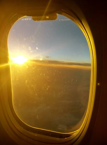 Pôr-do-sol atrás da nuvem e da janela no avião. luz do sol — Fotografia de Stock