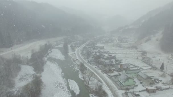 Fliegen über Dorf im Winter. Schneesturm — Stockvideo