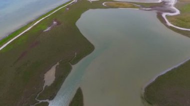 An impressive bird`s eye view of the Black Sea shelf with surrealistic small lake having the form of a girl covered with green weeds on a sunny day in summer. The seascape looks wild and rough