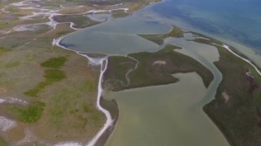 An impressive bird`s eye view of the Black Sea shore with curvy ponds, tiny patches of weed and wetland, and a country road on a sunny day in summer. The skyscape is grey and cloudy