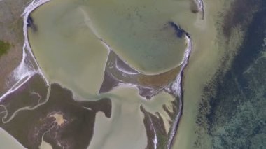 A splendid bird`s eye view of the Black Sea shallow with salty lines making some arty drawings and green wetland on a sunny day in summer. The dark blue waters look gorgeous