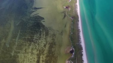 A bird`s eye view of the Black Sea sandy stripe separating the sea waves in dirty green and bright turquoise on a sunny day in summer. The straight spit looks like a line between hell and heaven