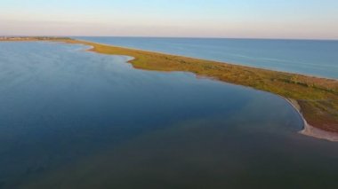An impressive bird`s eye view of the Black Sea shelf with sandy spits covered with wetland from grass and weed. The bright blue waters are rippling on a sunny day in summer. It looks dreamlike