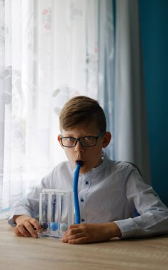 Genç çocuk derin nefes alma egzersizi yaptı ve spirometreyi teşvik etti. Normal derin nefes alma işlemine yardımcı olması için üç kez solunum egzersizi. 