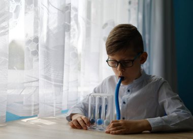 Genç çocuk derin nefes alma egzersizi yaptı ve spirometreyi teşvik etti. Normal derin nefes alma işlemine yardımcı olması için üç kez solunum egzersizi. 