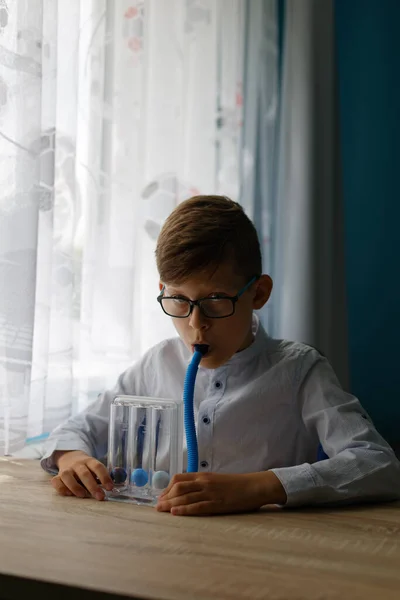 Young boy deep breathing exercise with triballs incentive spirometer. Threeflow respiratory exerciser for help perform normal deep breathing.