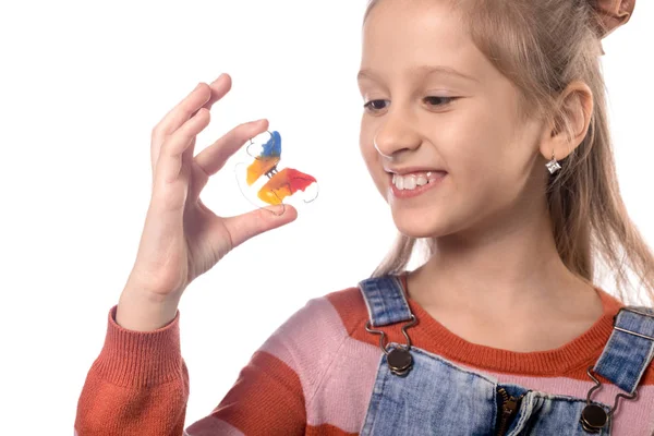 Ortodonti aletli küçük kız beyaz sırt çantasında izole edilmiş.