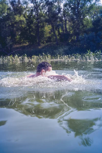 De jongeman die in de rivier zwemt — Stockfoto