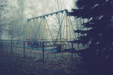 Sisli bir sonbahar sabahında terk edilmiş eski bir parkta sallanan tekneler..