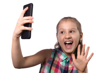 Küçük şirin kız telefonuyla selfie çekiyor. Beyaz arkaplanda stüdyo fotoğrafı